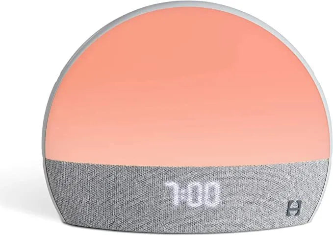 Hatch Restore smart clock in light grey with a night light and white noise machine on a bedside table