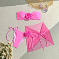Women's pink tube top swimsuit with large flower tie, matching skirt and pants.