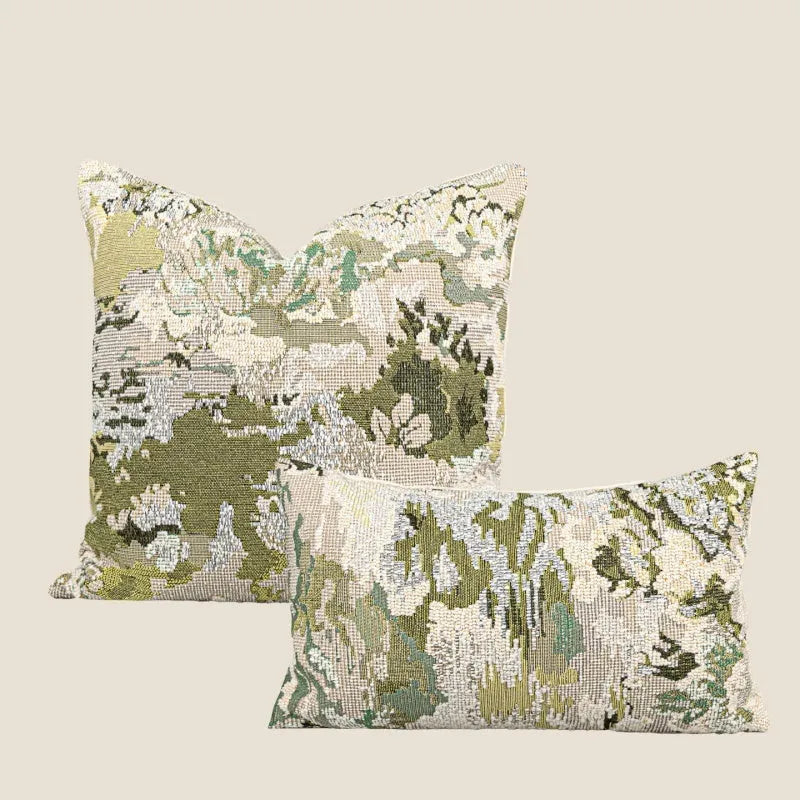 Antique green square pillow with abstract spring flowers pattern on a grey sofa.