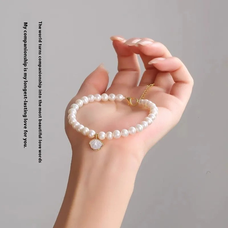 Women's freshwater pearl bracelet with a gold-toned fan charm on a 16cm elastic string.