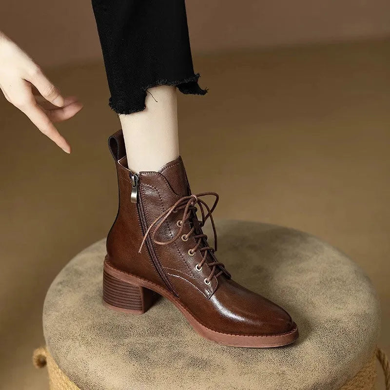 Women's black pointed-toe short tube ankle boots with a low block heel on a neutral background.