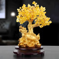 Citrine-coloured resin turtle money tree ornament on a neutral background.