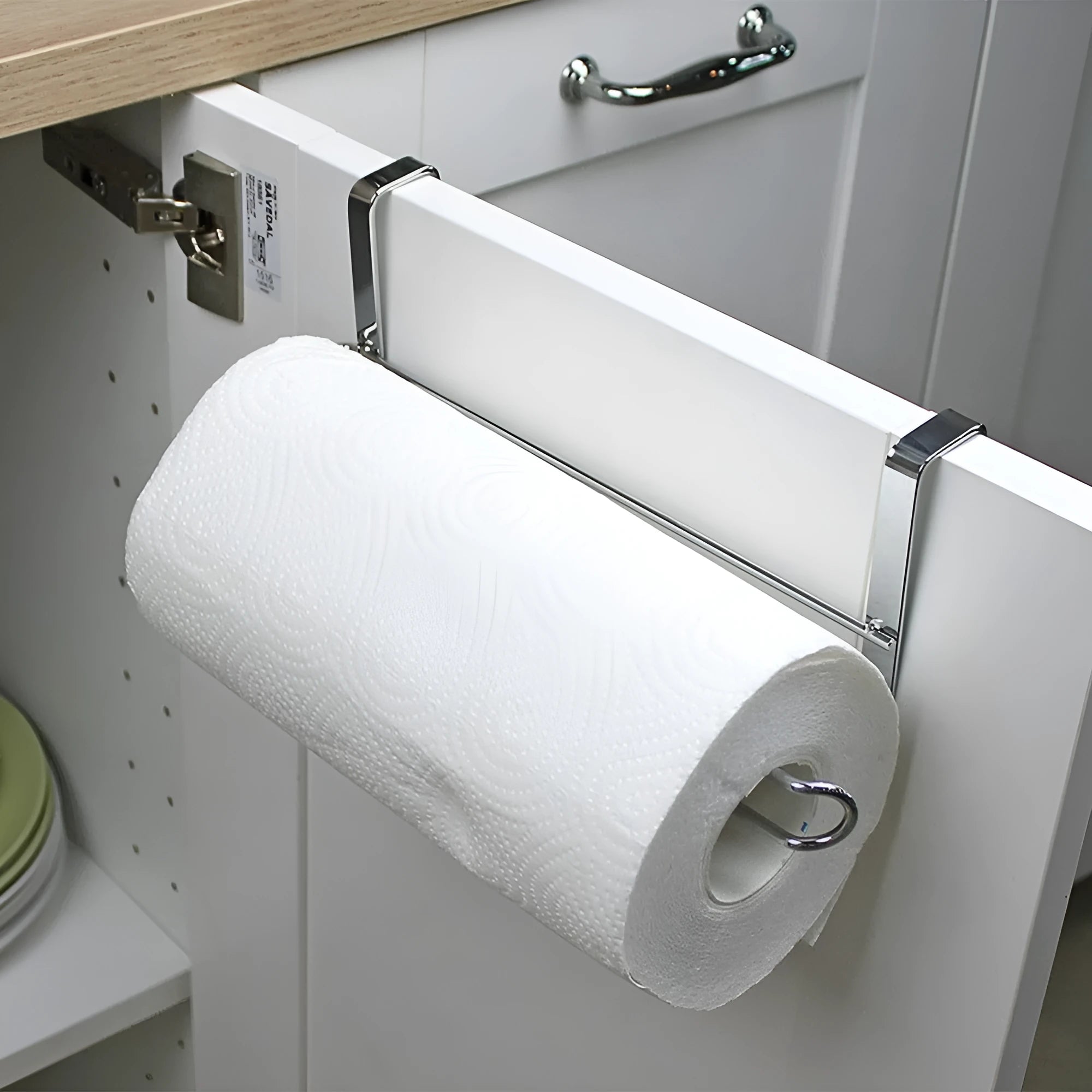 Silver stainless steel paper towel rack mounted on back of white cabinet door.