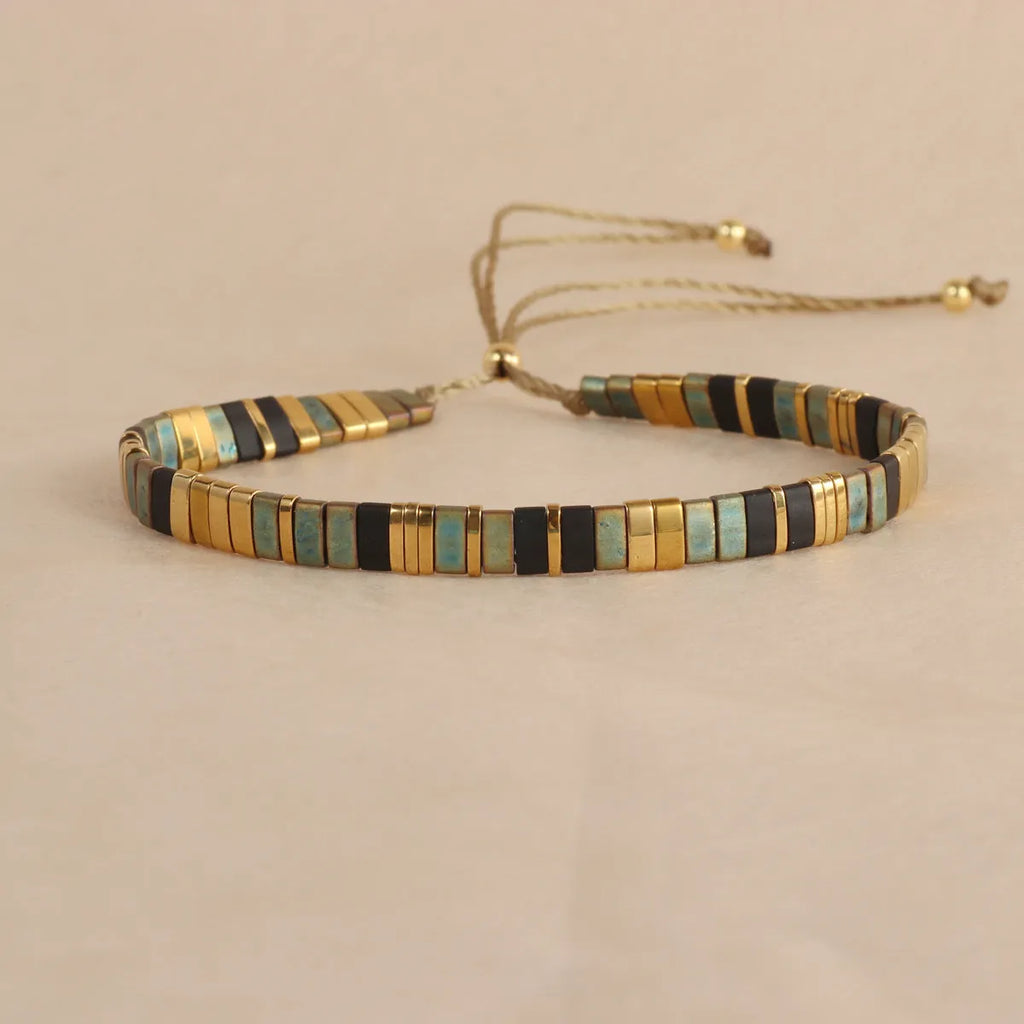 Adjustable geometric beaded bracelet with pull beads in milky white, black, green, blue or red.