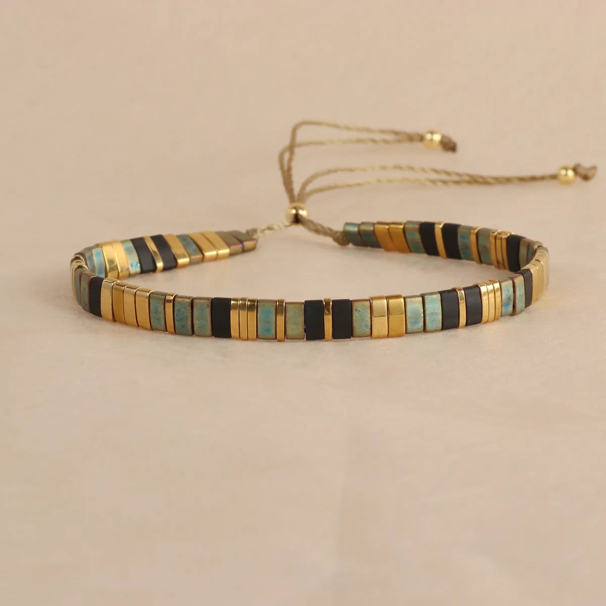 Adjustable geometric beaded bracelet with pull beads in milky white, black, green, blue or red.