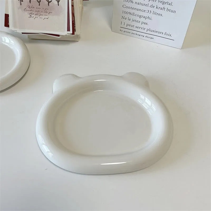 White porcelain plate with bear doodle design, shown as a plant pot tray.