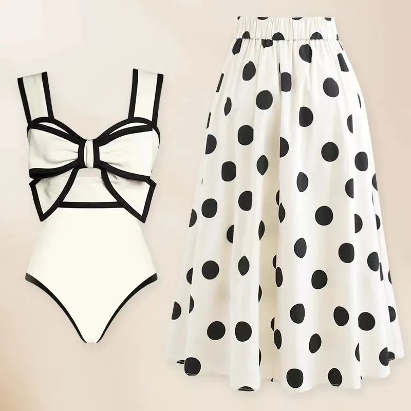 Women's black one-piece swimsuit with a white flared skirt and a bow detail.