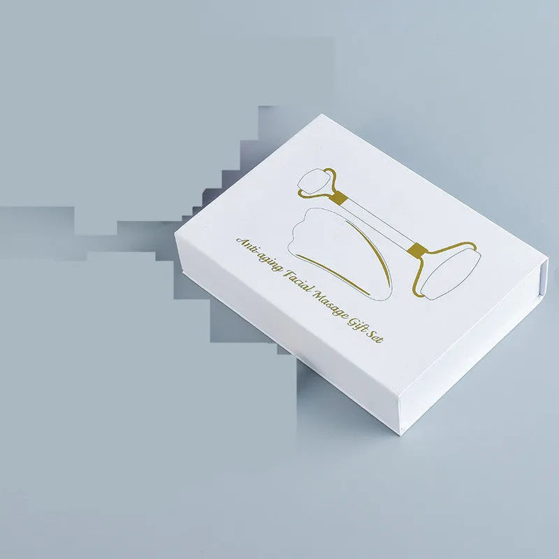 Natural white jade double-headed facial roller and gua sha board set on a plain background.