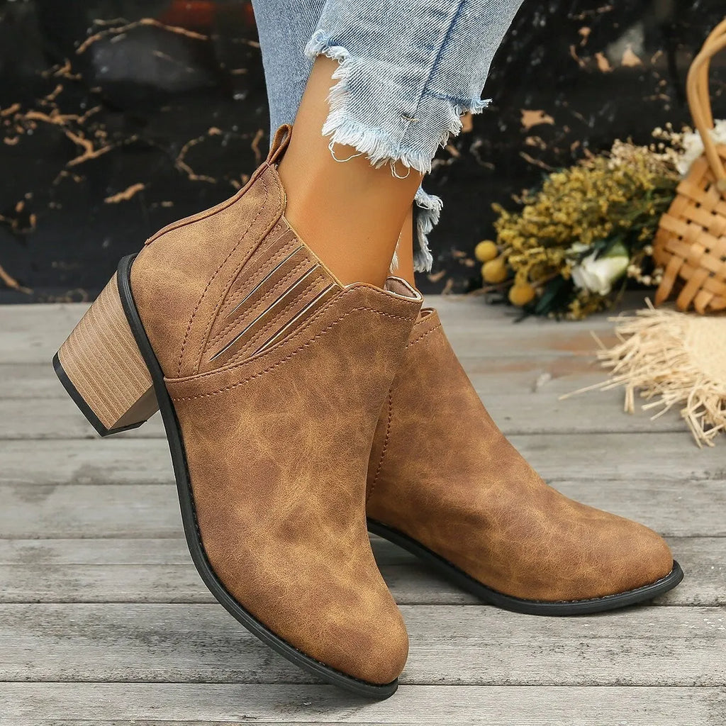 Black women's slip-on ankle boots with a pointed toe and a thick, low square heel on a rubber sole.