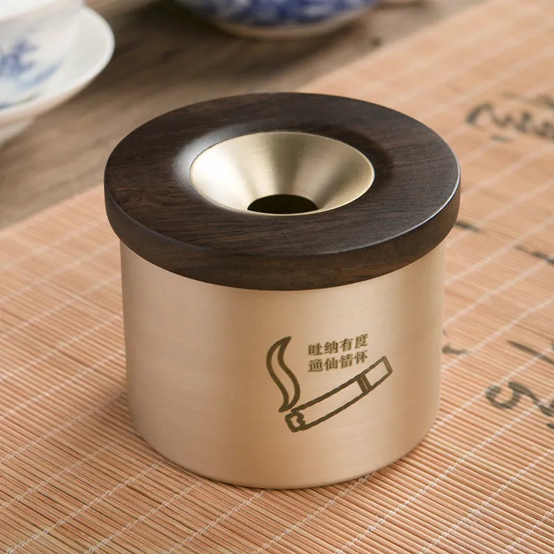Brass ashtray with wooden lid in blackwood or rosewood finish, 6 cm diameter, on a table.