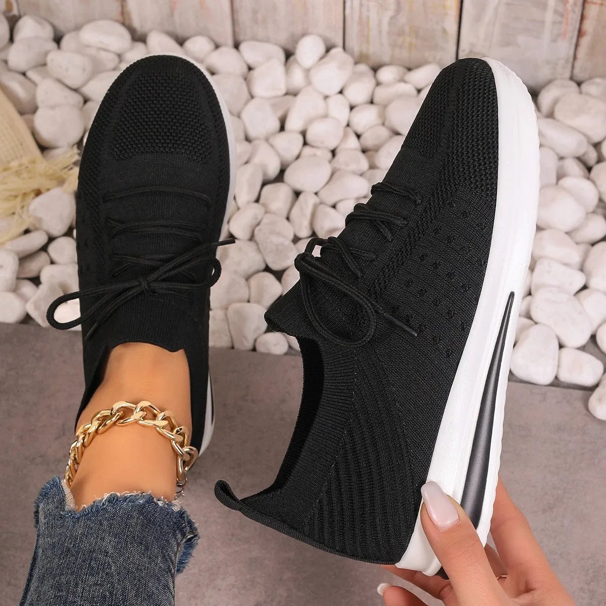Women's low-top black fly-knit sneakers with round toe and white lace-up front.