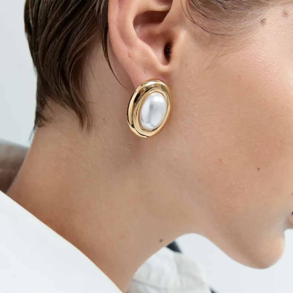 A pair of gold-colour stainless steel ear studs with a vintage pearl centre and butterfly clutch backs.