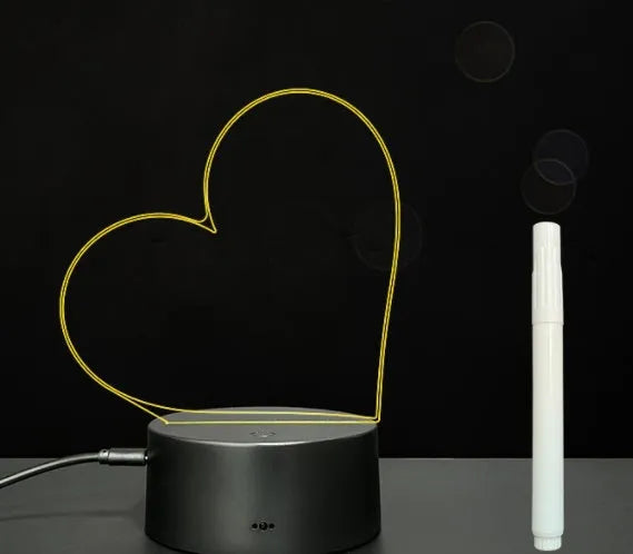 3D acrylic LED message board night light with remote control and marker pen on a desk.