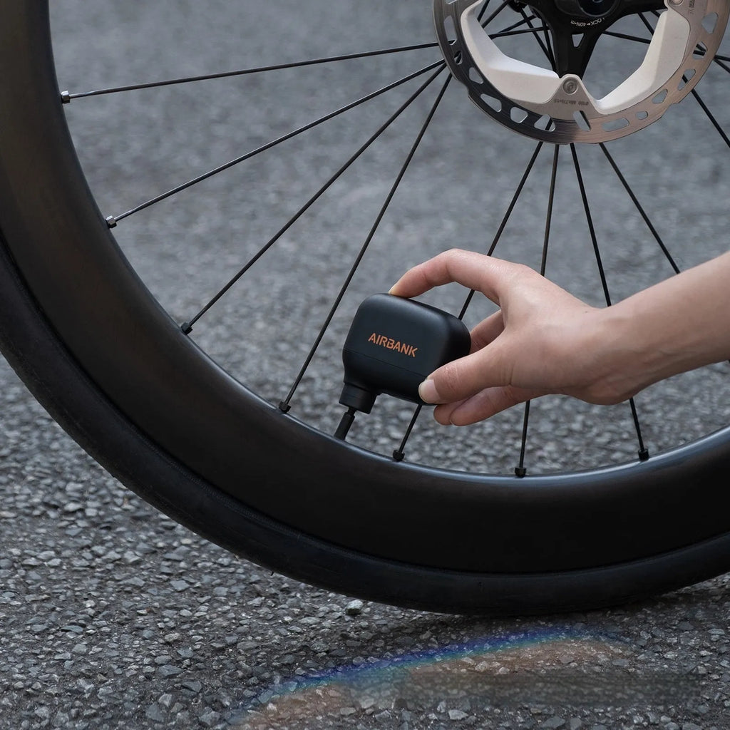 Black AS100 mini electric bike pump with USB charging cable and waterproof bag.