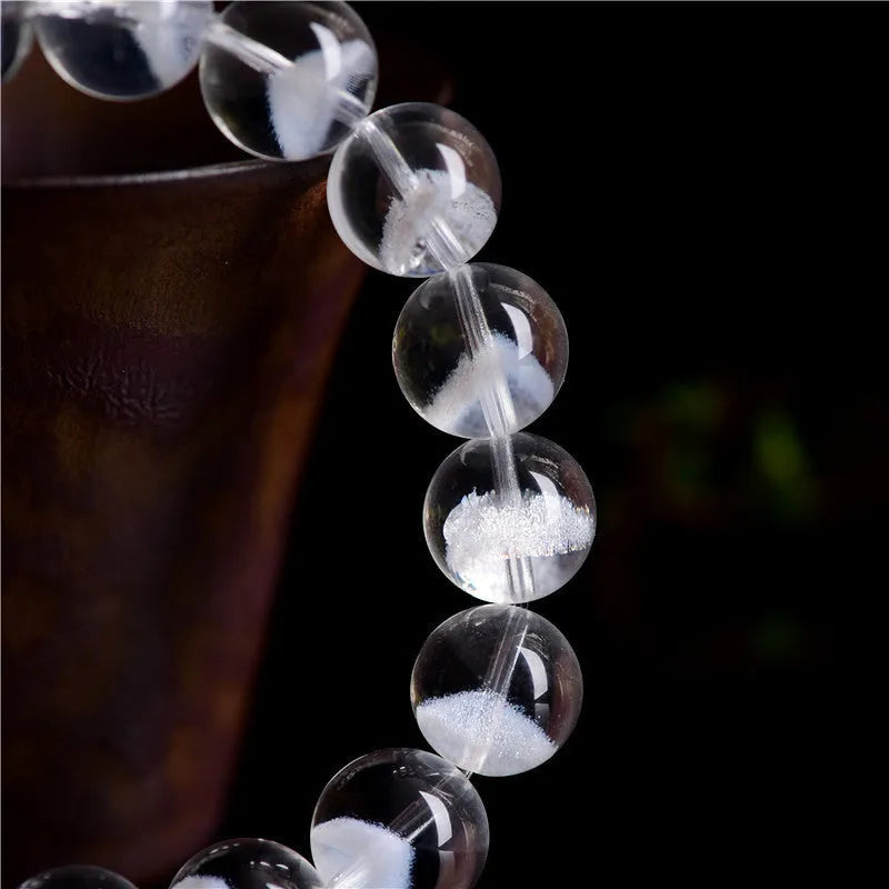 Women's white crystal ghost pyramid bracelet with ruyi charm on a wrist, showing bead detail.