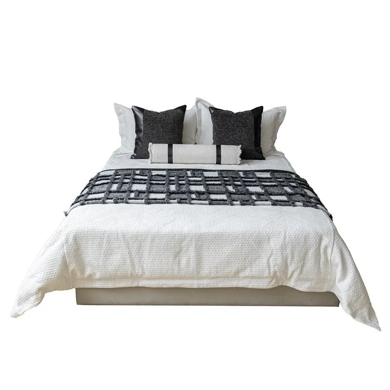 Modern minimalist bedding set with grey and white plaid blanket, pillowcase, and round pillow on bed