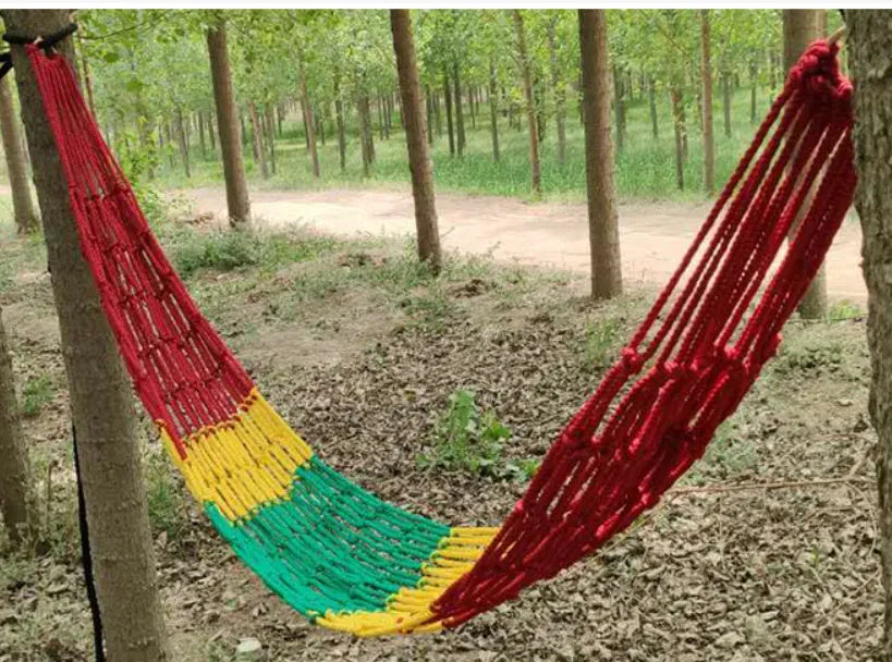 Bold style outdoor nylon rope mesh hammock hung between two trees.