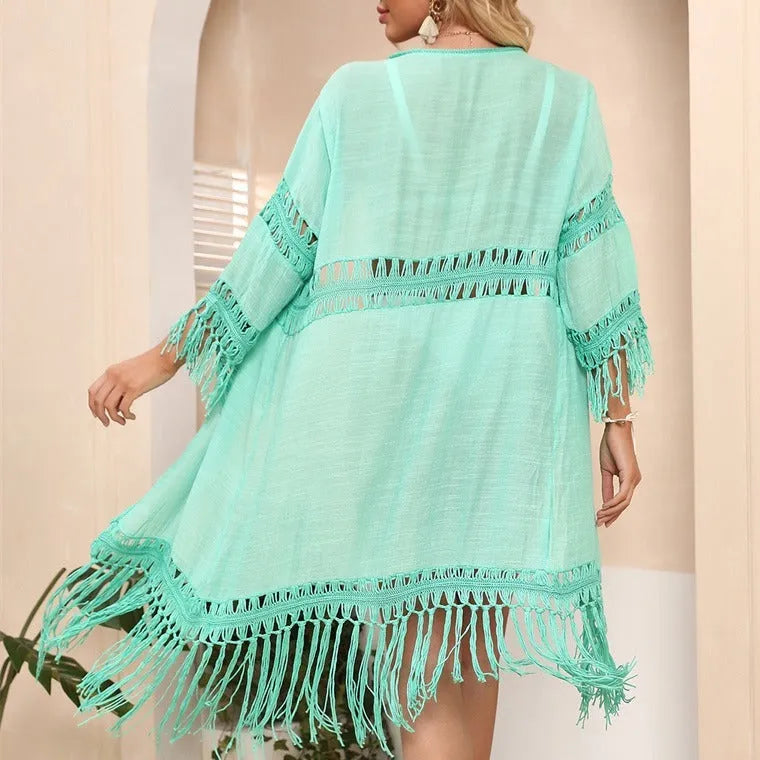 Hand-crocheted yellow acrylic beach cover-up cardigan with loose stitches and tassel trim on a mannequin.