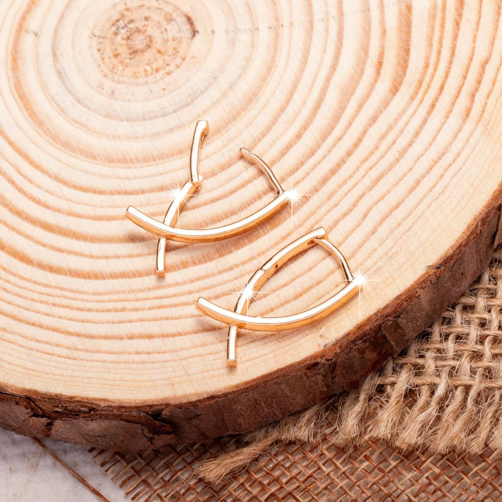 Rose gold coloured cross-shaped drop earrings for women on a white background.
