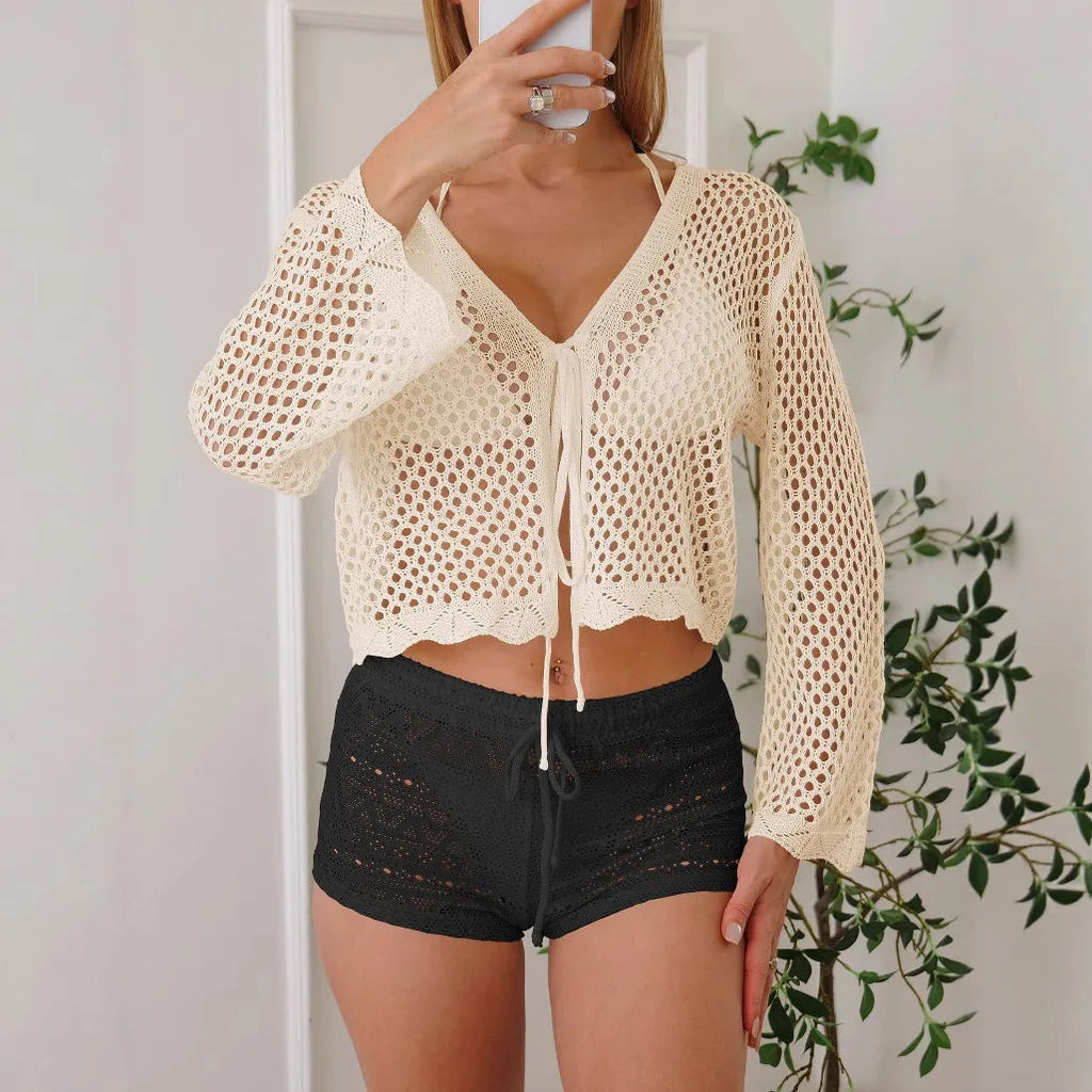 Short apricot coloured women's cardigan blouse with long bell sleeves on a hanger.