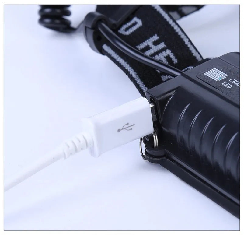 Fixed focus LED head torch with head strap, shown with its included charger.
