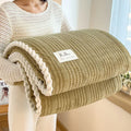 Solid colour jacquard milk velvet blanket in cream white, folded on a sofa, showing textured weave pattern