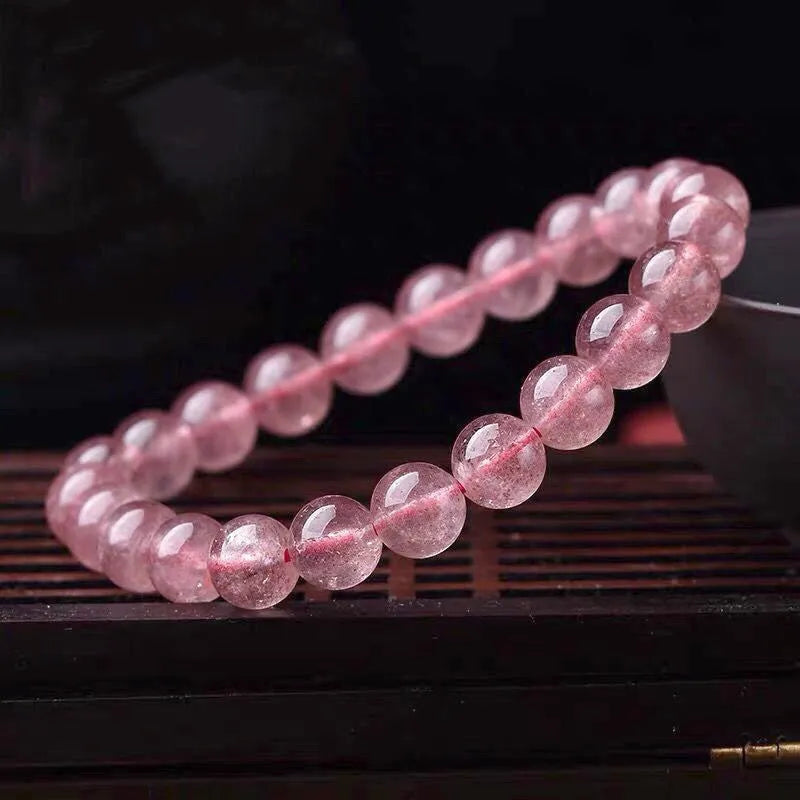 Women's strawberry quartz bracelet with polished beads on elastic string, shown in 6mm, 8mm, and 10mm size options.