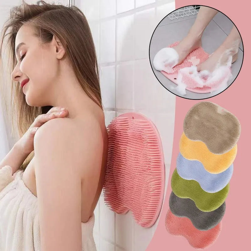 Orange non-slip massage bath brush with suction cups and soft silicone bristles on a bathroom floor.
