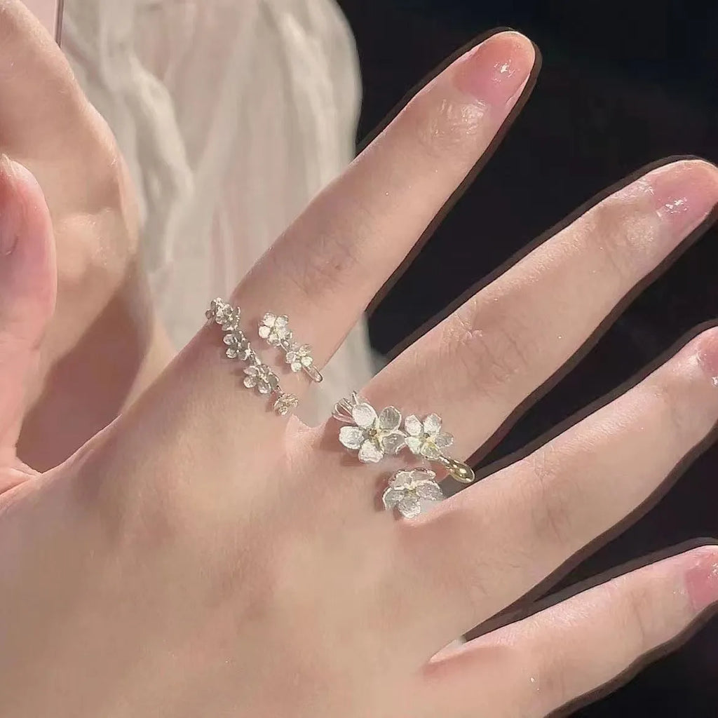 Three-dimensional zinc alloy jasmine flower ring with open mouth design on a finger.