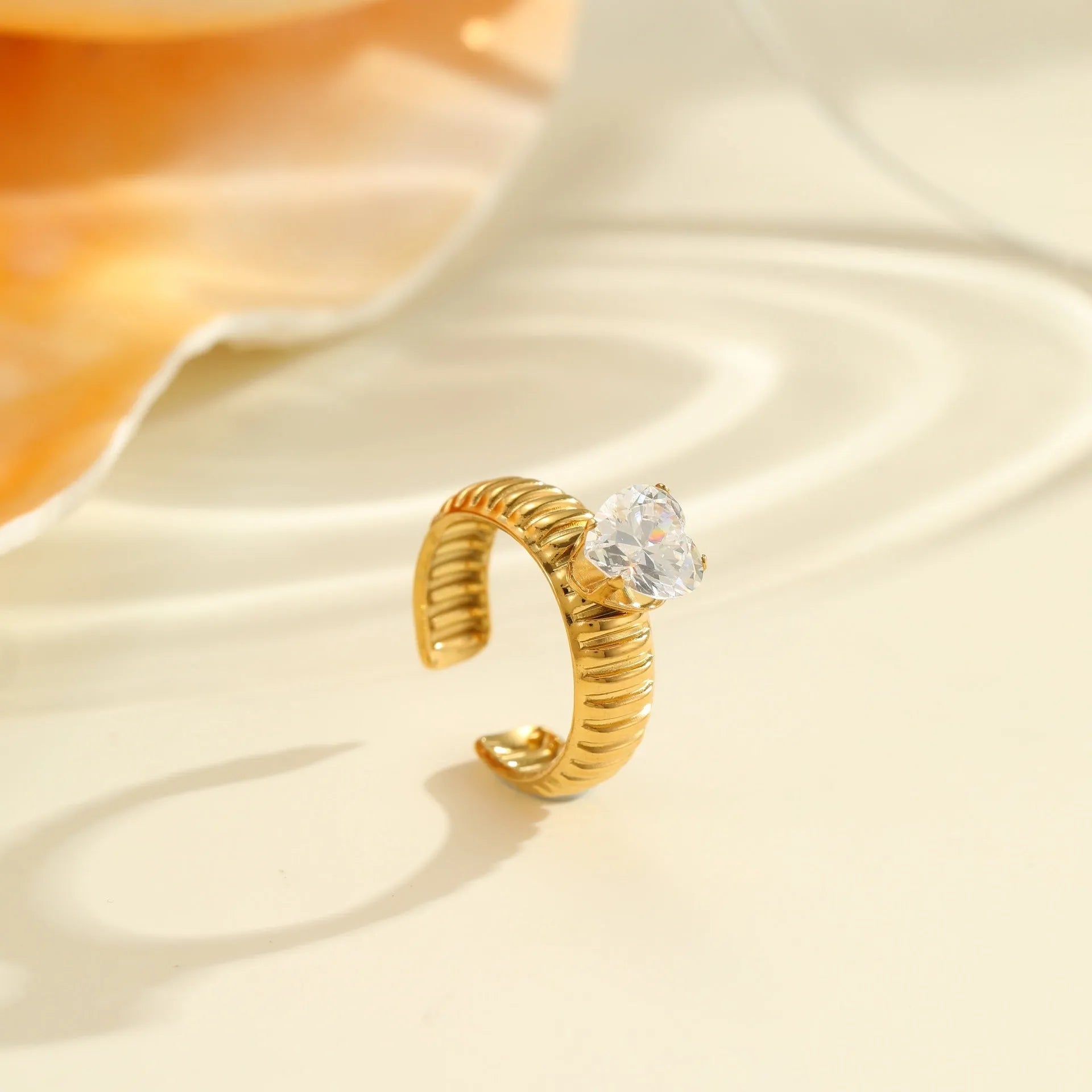 Gold-toned stainless steel ring with zircon details in a geometric heart shape design on a finger.