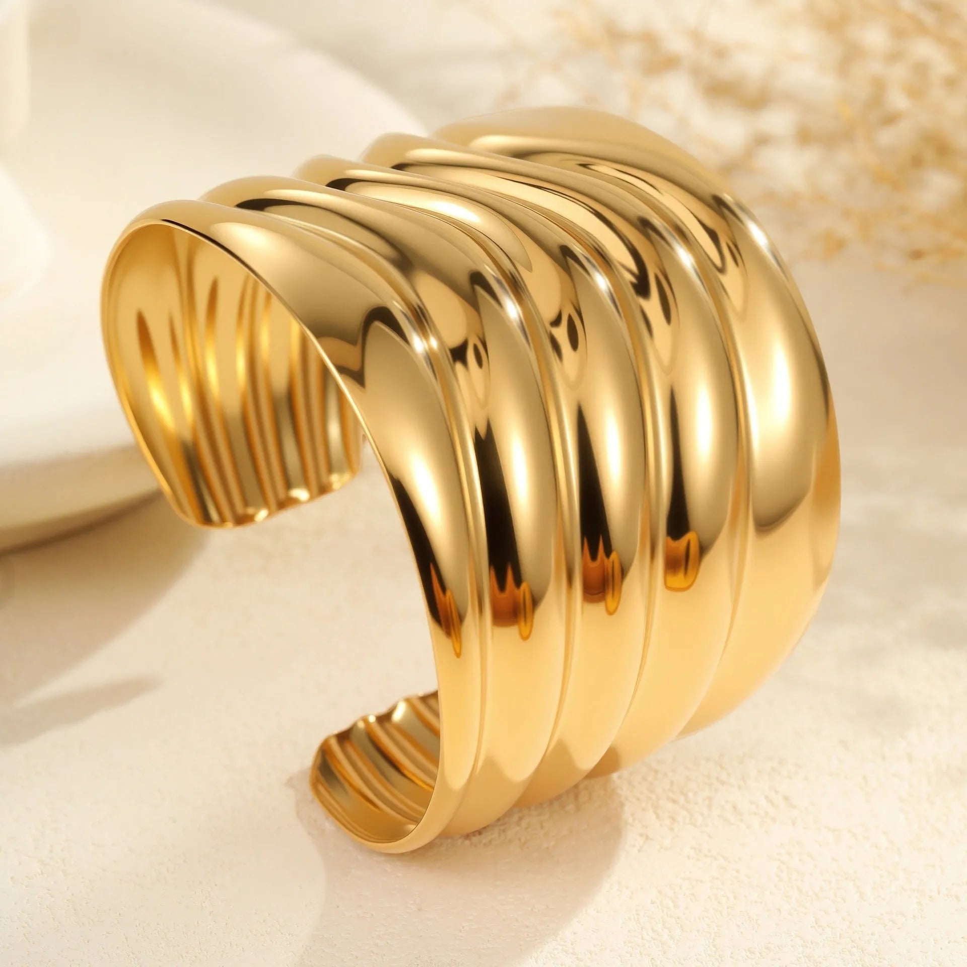 Women's wide stainless steel bracelet with geometric wave modelling and gold plating