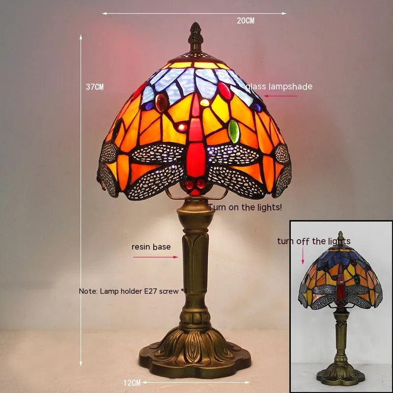 Tiffany style stone table lamp with blue dragonfly design on a bedside table.