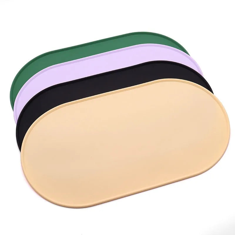A green silicone placemat for cat food and water bowls on a wooden floor.