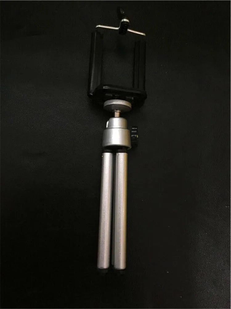 Black and silver metal desktop phone holder with an adjustable two-section bracket on a wooden desk.