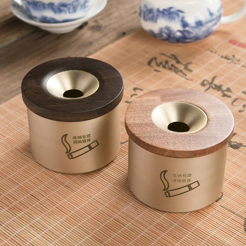 Brass ashtray with wooden lid in blackwood or rosewood finish, 6 cm diameter, on a table.