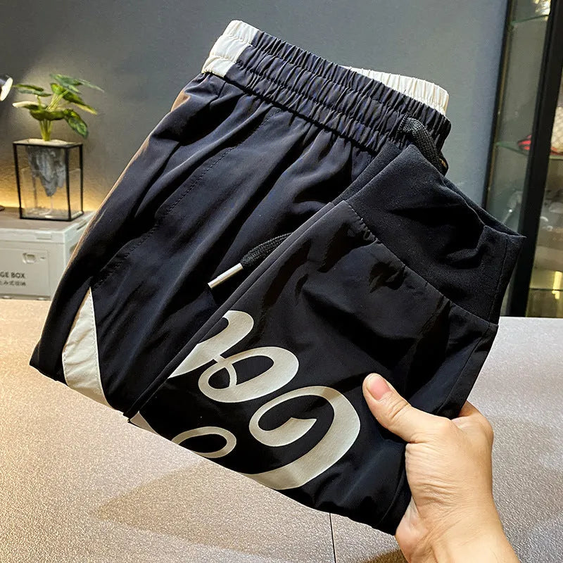 Men's solid black cropped trousers with banded ankles made from ultra-thin ice silk and cotton blend fabric.