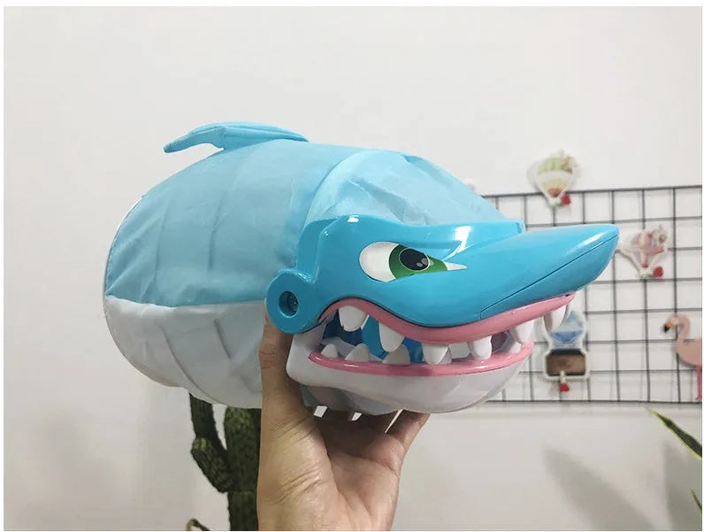 Great white shark tricky toy with small plastic fish inserted in its mouth on a tabletop