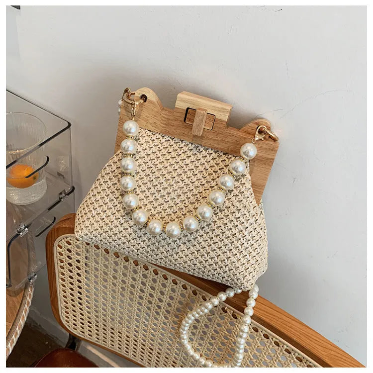Women's woven straw shoulder bag with pearl chain details showing interior organisation compartments