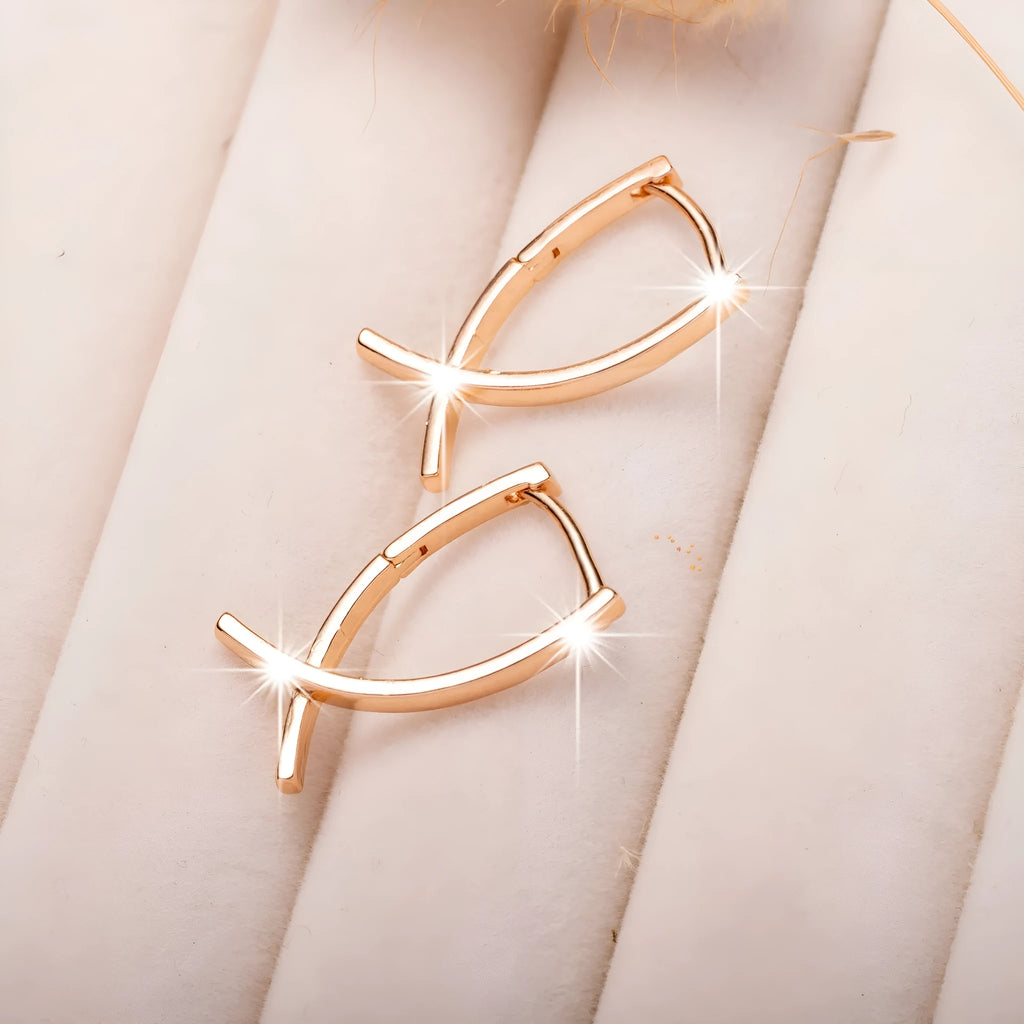 Rose gold coloured cross-shaped drop earrings for women on a white background.