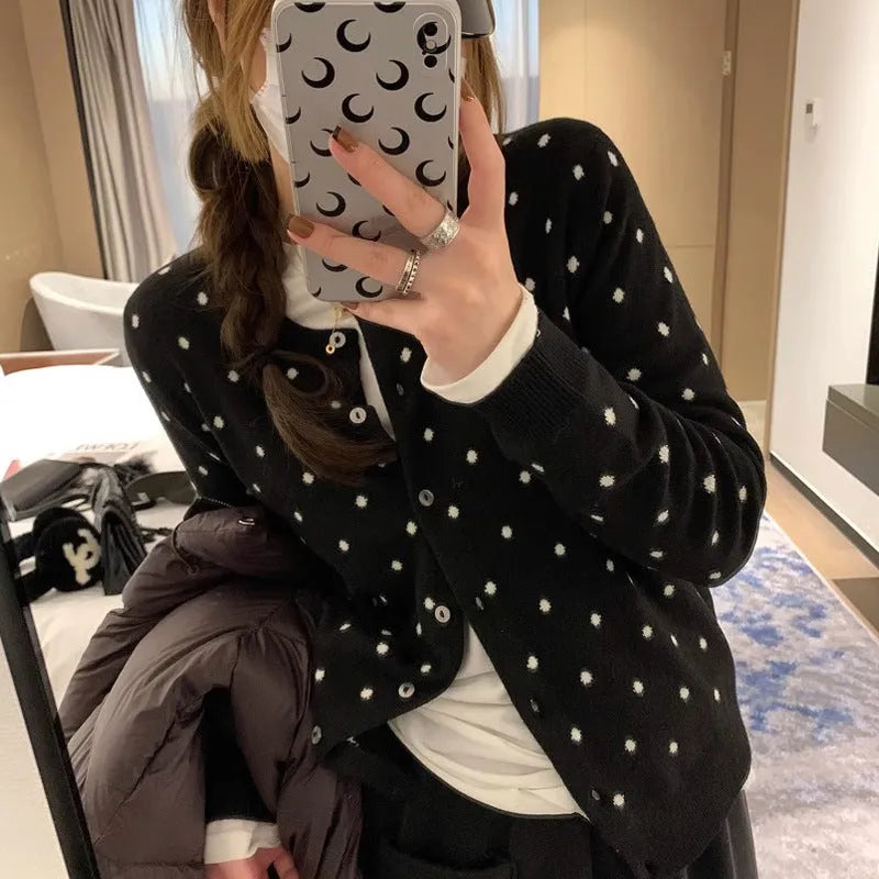 Women's grey dot pattern knitted cardigan with crochet flower detailing on mannequin