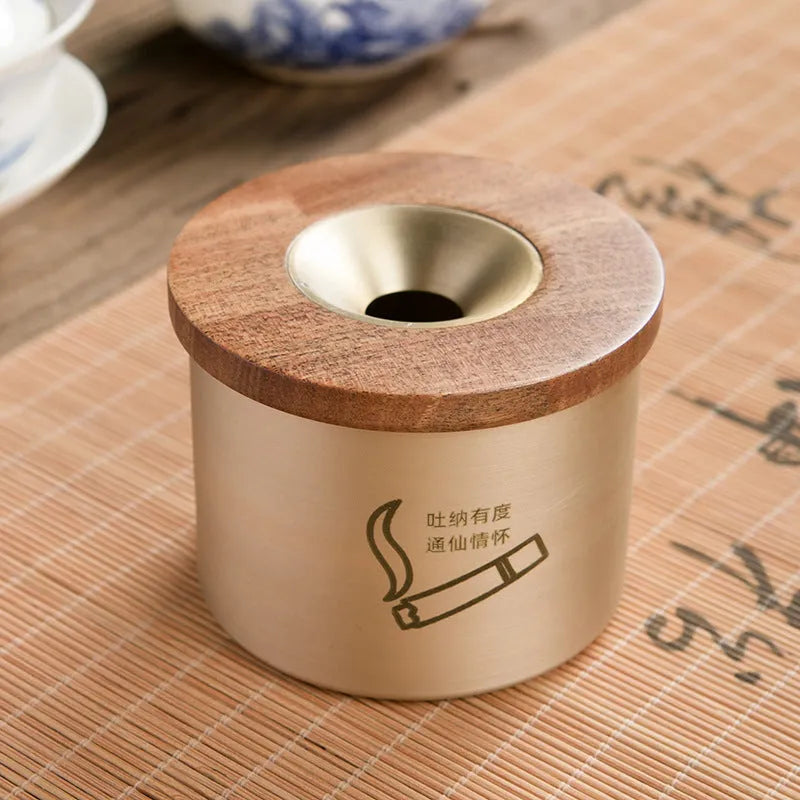 Brass ashtray with wooden lid in blackwood or rosewood finish, 6 cm diameter, on a table.