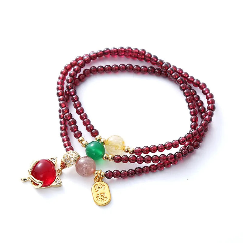 Purplish red garnet bead bracelet with a silver fox charm and adjustable rope fastening.