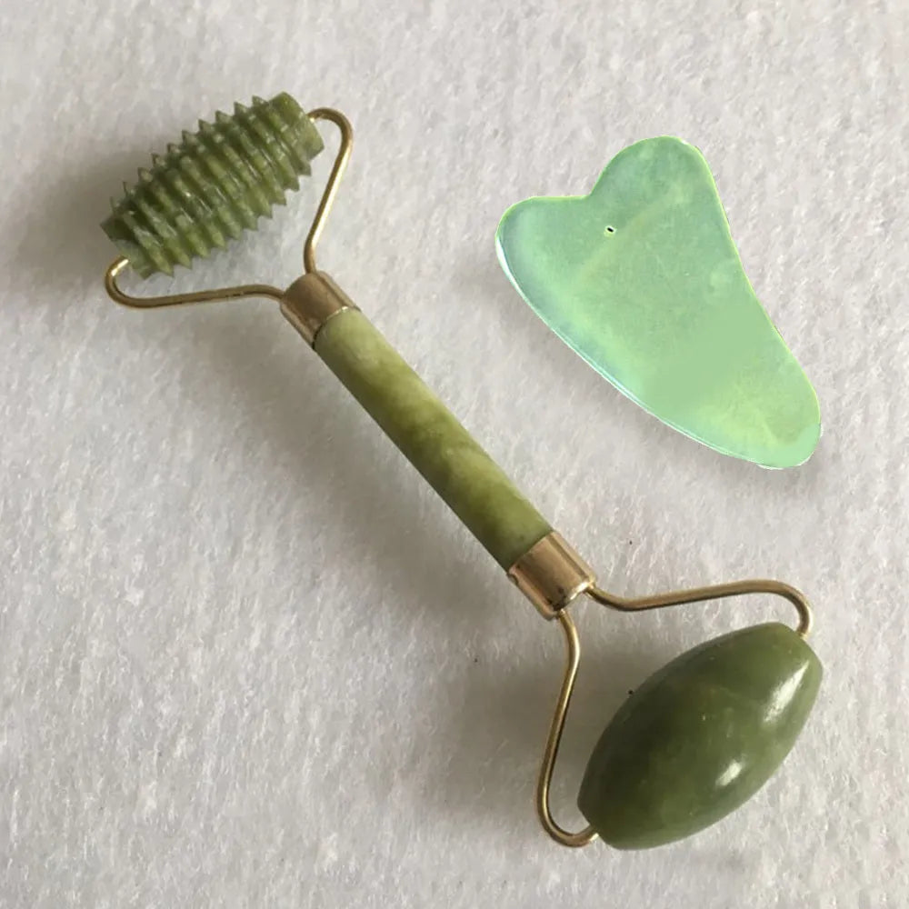 Natural green jade face massager roller and scraper set on a clean surface