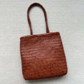 Brown woven leather tote bag with three-dimensional pockets and shoulder straps