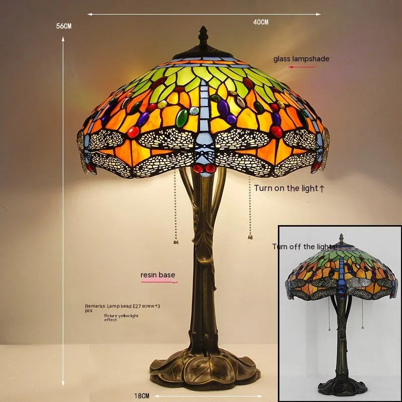 Tiffany style stone table lamp with blue dragonfly design on a bedside table.