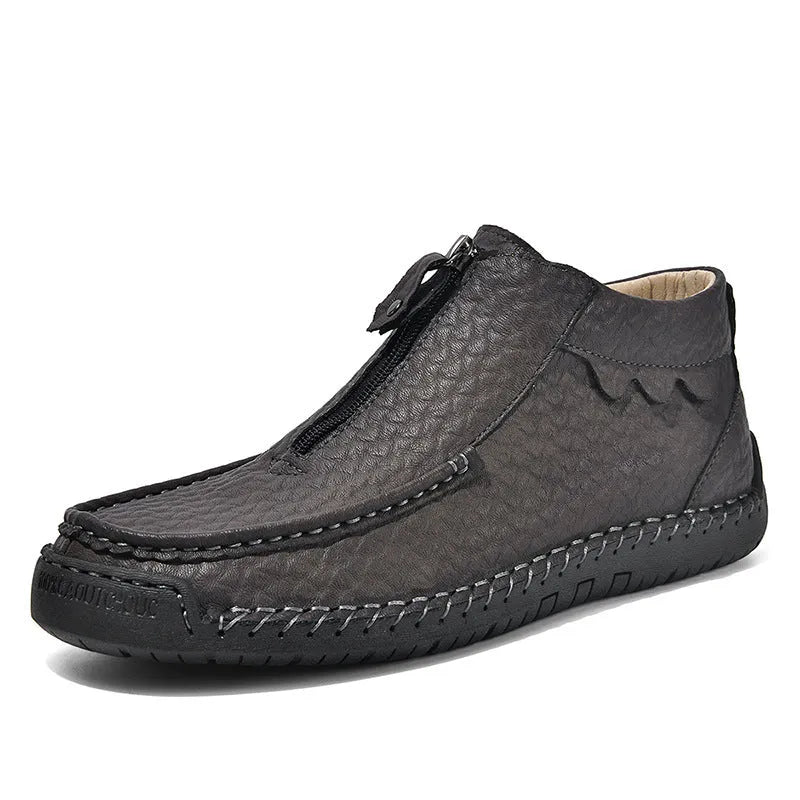 Men's black slip-on leather loafers with round toe and rubber sole, shown in a casual setting.