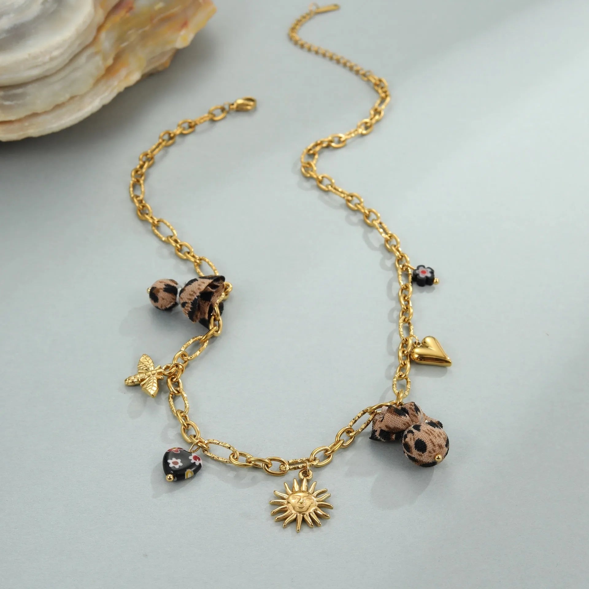 Stainless steel necklace with gold electroplated pendant showing leopard and heart flower designs