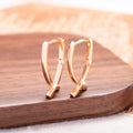 Rose gold coloured cross-shaped drop earrings for women on a white background.