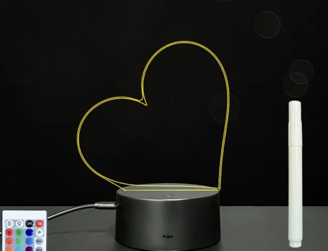3D acrylic LED message board night light with remote control and marker pen on a desk.