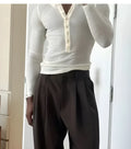 Man wearing a cream-coloured ribbed long-sleeve henley top with button detail.